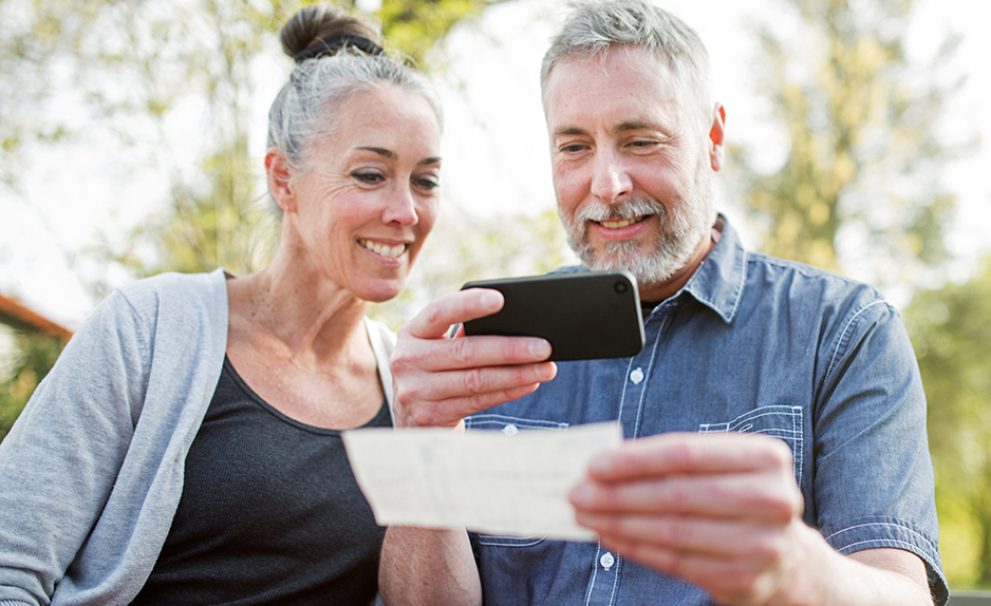 A middle aged couple doing a mobile deposit using their smartphone